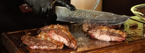 Fleisch, das mit einem Messer in kleinere Stücke geschnitten wird
