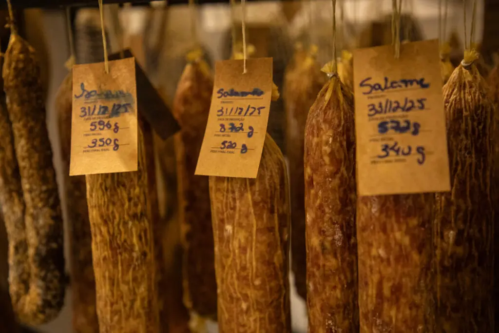 Würste und Salami, die in einer Metzgerei mit Gewichten hängen
